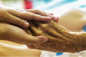 palliative care patient holding hand of loved one