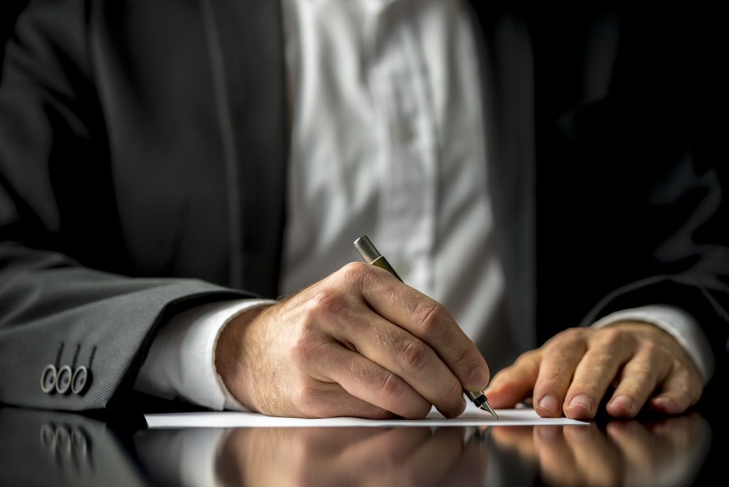 Conceptual image of a man signing a last will and testament document.