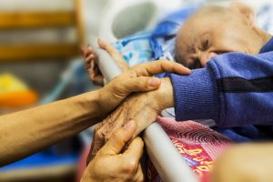 hospice care patient holding hands of loved one