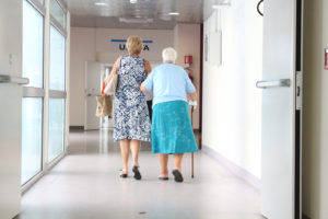 volunteer walking elderly woman down hallway